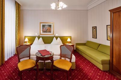Zimmer mit Doppelbett, Couch, bodentiefen Fenstern, Schrank und Sitzecke